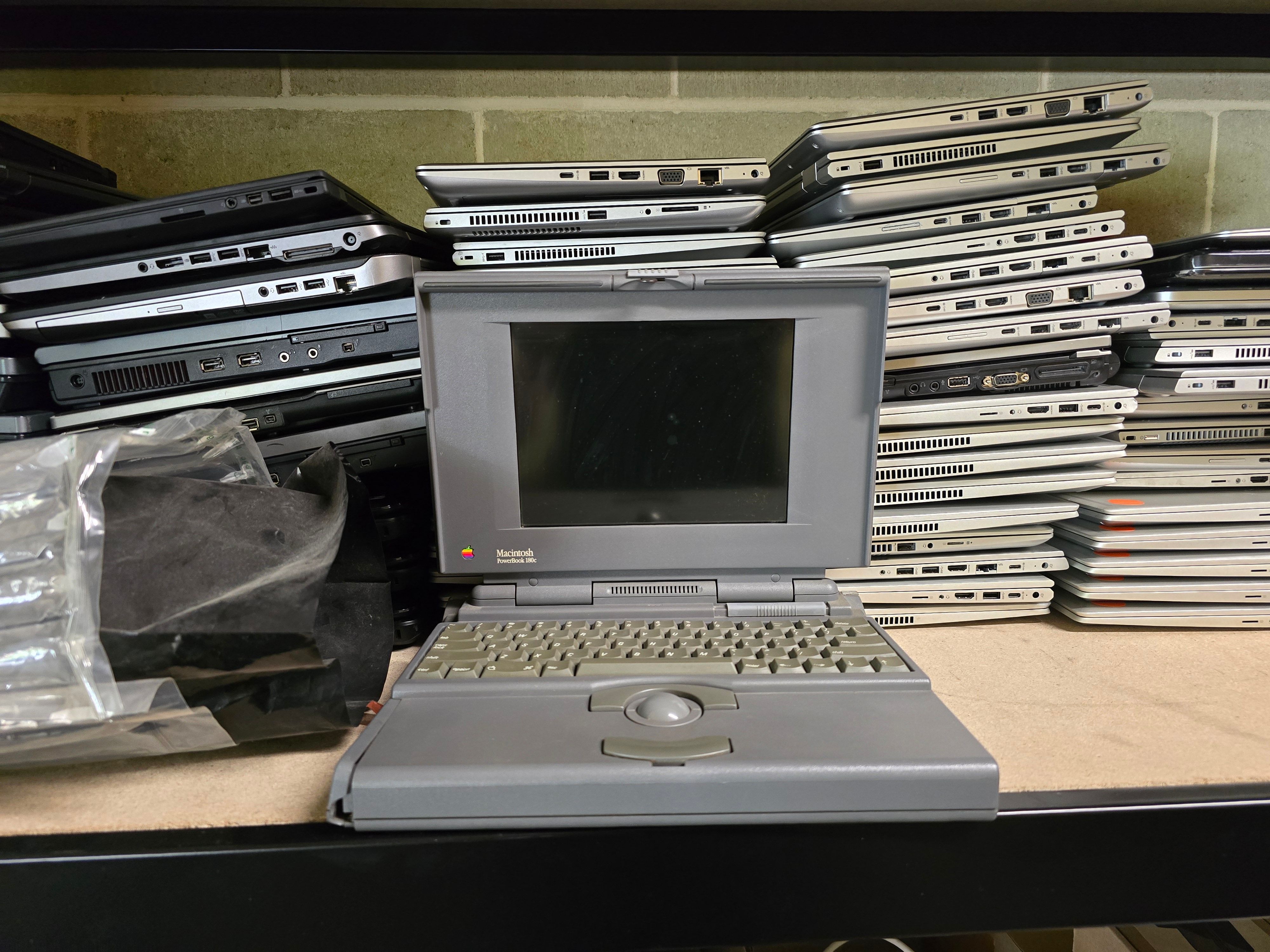 05nov24 - very old laptop in front of a stack of 80 new ones